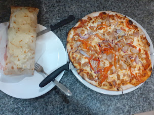 Une pizza tout juste sortie du four, servie avec un roulé gratiné